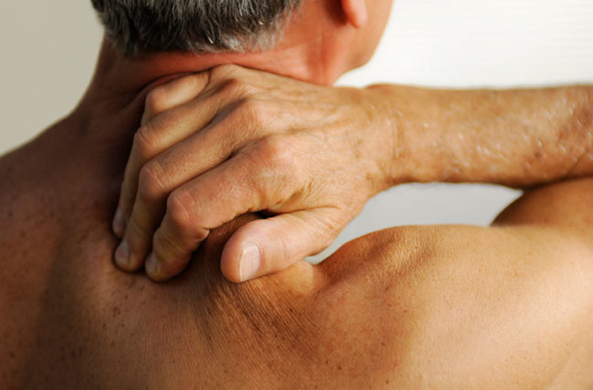 A man rubs the back of his neck with his right hand